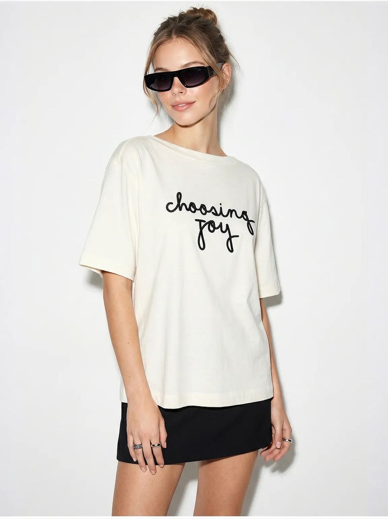 T-shirt feminina de algodão com decote barco e estampado lucci Branco sujo - Kiabi